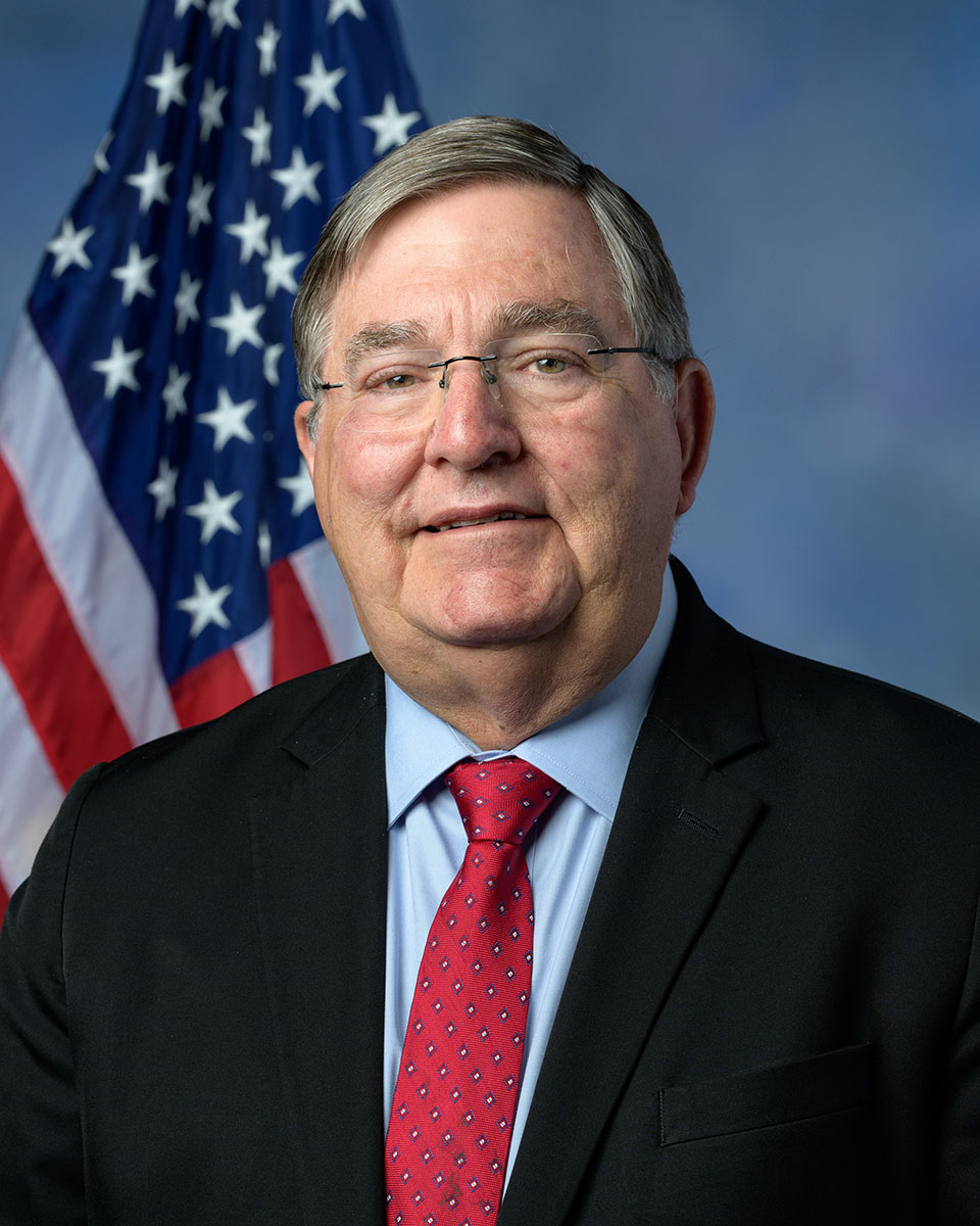 UNT alumnus and former congressman Dr. Michael Burgess poses in front of the American flag