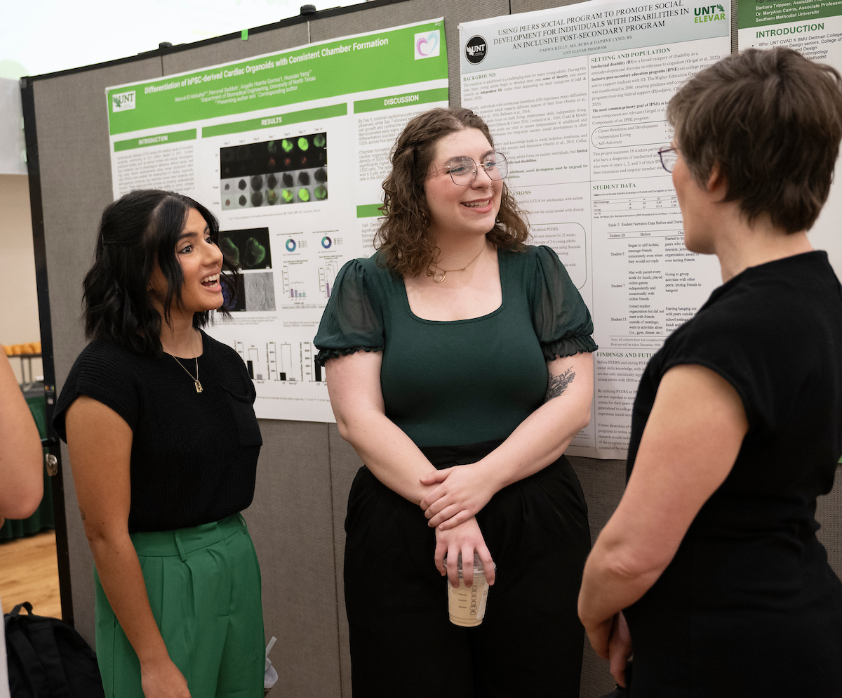 A trio of women in front of a research poster