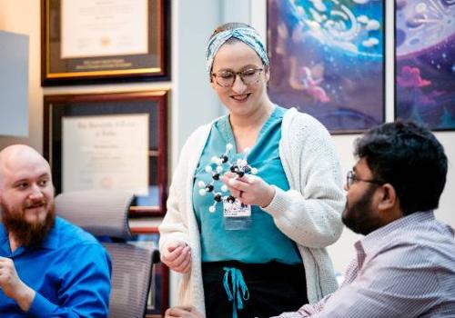 Nicole Everitt Holds a Model of a Molecule in the UNT Dallas STEM Center During a Tutoring Session